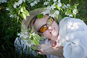 Outdoor portrait of a beautiful blonde middle-aged woman near blossom apple trees with white flowers