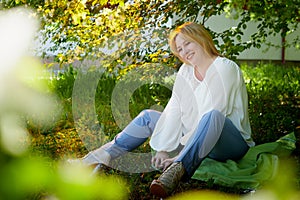 Outdoor portrait of a beautiful blonde middle-aged woman near blossom apple trees with white flowers