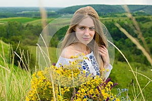 Outdoor portrait of beautiful blonde woman, attractive young girl in camomile field with flowers. Young beautiful girl in the fiel