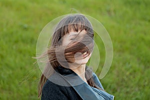 Outdoor portrait of beautiful girl laughing while the wind moves