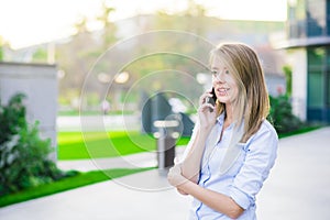 Outdoor portrait of a beautiful happy brunette woman or businesswoman in her thirties talking on her cell phone