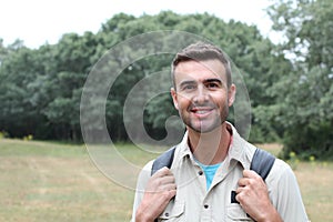 Outdoor portrait in of beautiful happy handsome young man smiling and laughing with perfect teeth hiking with black rucksack