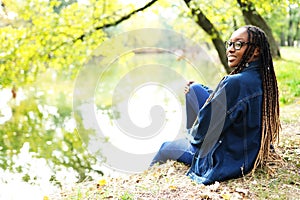 Outdoor portrait of beautiful happy laughing mixed race African American girl teenager female young woman sitting in the park near