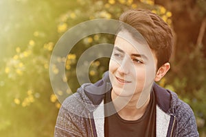 Outdoor portrait of beautiful happy teenager guy under a sunny d