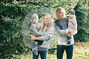 Outdoor portrait of beautiful happy young family posing in pine forest