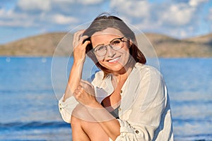 Outdoor portrait of beautiful smiling middle aged woman looking at camera