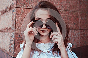 Outdoor portrait of beautiful stylish woman in glasses on street. Fashion model wearing summer clothing and accessories