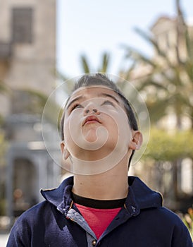 Outdoor portrait of a cute litlle boy who looking up