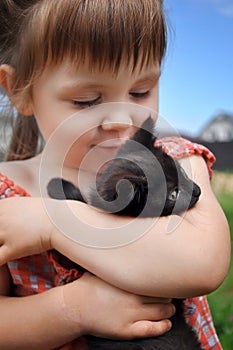 Outdoor portrait of a cute little girl with small kitten, girl playing with cat on natural background