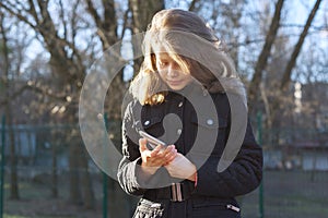 Outdoor portrait girl child of 8, 9 years old with smartphone