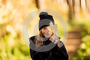 Outdoor portrait of happy blonde child girl holding yellow leaf. Little girl walking in the autumn park or forest. Warm sunny