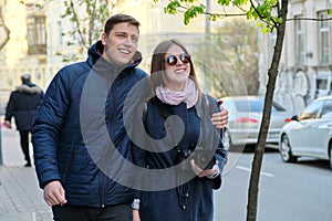 Outdoor portrait of happy couple in love walking along street of winter spring city