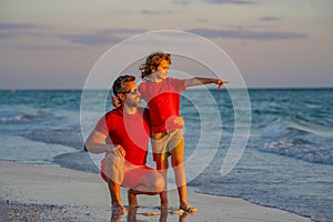 Outdoor portrait of happy father and son walking on sunny ocean beach. Father and son walk in sea beach. Concept of