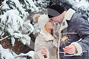 Outdoor portrait of happy romantic couple celebrating Christmas with burning fireworks in snowy forest