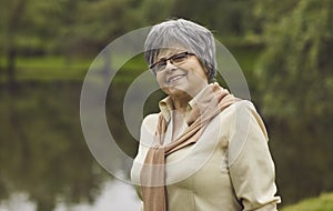 Outdoor portrait of happy senior woman against background of summer park greenery