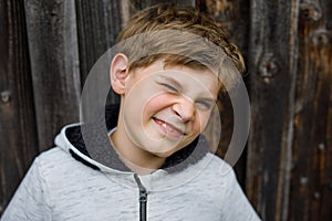Outdoor portrait of happy smiling school kid boy wearing rain jacket on rainy cloudy day. Handsome healthy child in