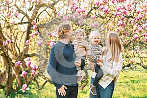 Outdoor portrait of happy young family playing in spring park