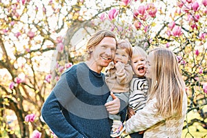 Outdoor portrait of happy young family playing in spring park