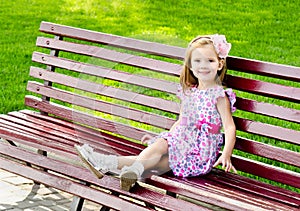 Outdoor portrait of little girl sitting on a bench
