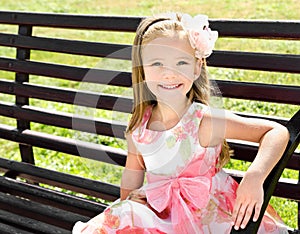 Outdoor portrait of little girl sitting on a bench