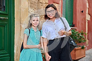 Outdoor portrait of mom and daughter 10, 11 years old on the street of old city looking into the camera