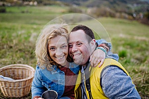 Outdoor portrait of mother hugging her grown up son with Down syndrome, motherhood concept.