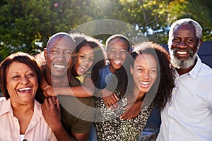 Outdoor Portrait Of Multi-Generation Family In Garden At Home Against Flaring Sun