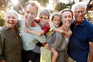 Outdoor Portrait Of Multi-Generation Family Walking In Countryside Against Flaring Sun