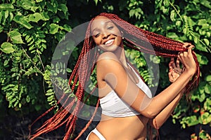 Outdoor portrait of natural Beautiful young African American woman long red braids hair style and perfect white teeth