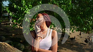 Outdoor portrait of natural Beautiful young African American woman long red braids hair style and perfect white teeth