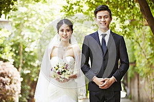Outdoor portrait of a newly-wed asian couple