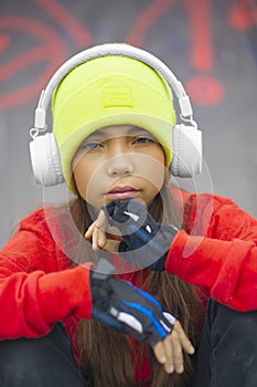 Outdoor portrait of a nine-year-old girl in headphones close-up. She is preoccupied with the issues of growing up and