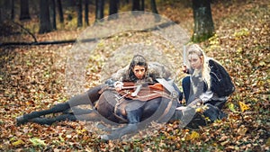 Outdoor portrait of northern viking warrior women hiding and stalking prey on raid with their horse laying on forest