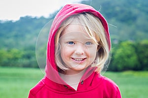 Outdoor portrait portait of cute child in a red hoodie