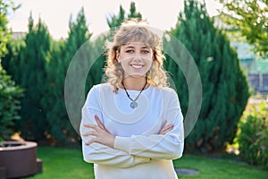 Outdoor portrait of positive teenage female looking at camera