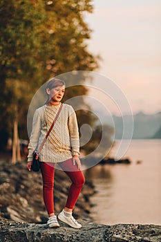 Outdoor portrait of pretty little girl resting by the lake