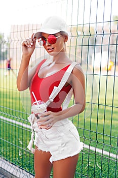 Outdoor portrait of pretty stylish fashion girl having fun drinking milkshake.