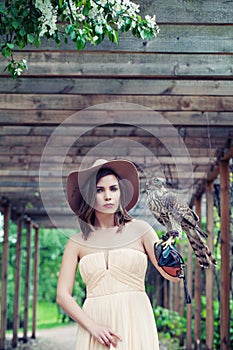 Outdoor portrait of pretty woman fashion model with hawk bird outdoors portrait