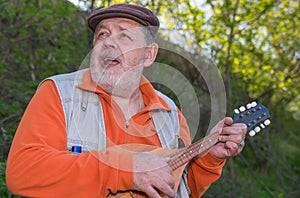 Portrait of senior man playing mandolin while singing