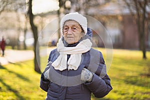Outdoor portrait of senior woman in jacket , scarf and head wear in winter. Happy retirement. Joyful elderly person posing in the