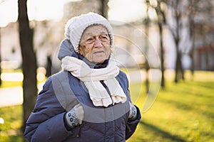 Outdoor portrait of senior woman in jacket , scarf and head wear in winter. Happy retirement. Joyful elderly person posing in the