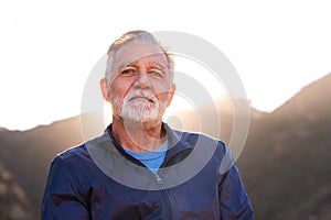 Outdoor Portrait Of Serious Hispanic Senior Man With Mental Health Concerns In Countryside