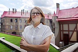 Outdoor portrait of smiling confident mature business woman with folded arms