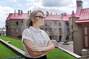 Outdoor portrait of smiling confident mature business woman with folded arms