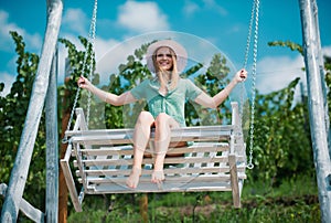 Outdoor portrait of a smiling happy girl. Sensual woman swinging on swing on summer nature, young sexy girl relaxing in