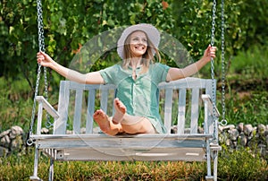 Outdoor portrait of a smiling happy girl. Young sexy woman is swinging on a swing in summer park garden. Sensual blonde