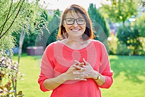 Outdoor portrait of smiling middle aged woman looking at camera
