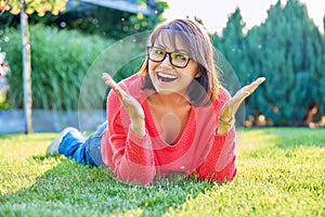 Outdoor portrait of smiling middle aged woman lying on grass