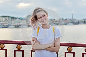 Outdoor portrait of smiling teenage girl of 15, 16 years old with folded arms