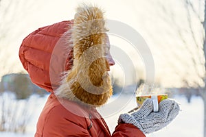 Outdoor portrait of a smiling young girl in a fur hood. Drinking